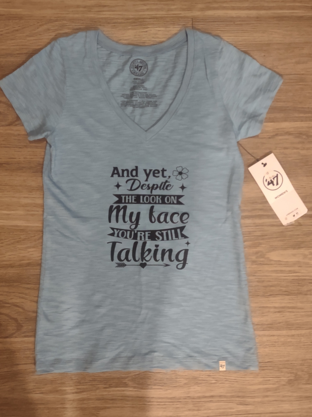 'And yet, despite the look on my face' Light Blue Graphic V-Neck Tee